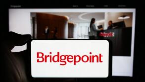 Person holding cellphone with logo of British investment company Bridgepoint Group plc in front of business webpage. Focus on phone display.