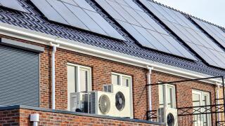 Air source heat pump unit installed outdoors at a modern home with solar panels in the Netherlands
