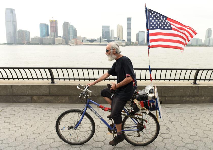 New York, USA - May 28, 2018:  A man with US flag on a bike in Battery Park City Esplanade in New York.