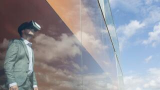 Businessman using virtual reality simulator glasses at modern window with cloud reflection