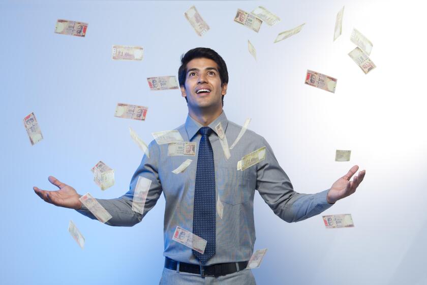 Money falling on a businessman standing with his arms outstretched