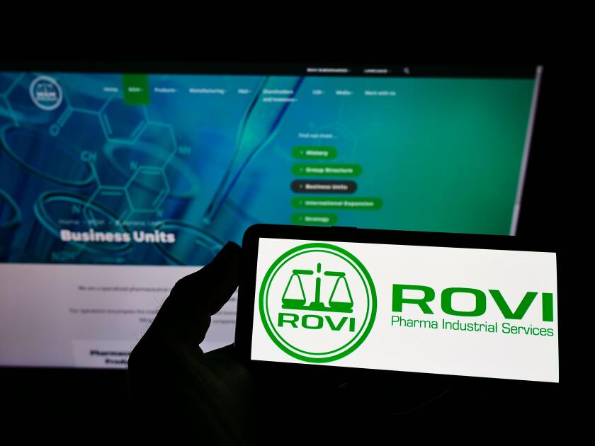 Person holding smartphone with logo of company Laboratorios Farmaceuticos Rovi S.A. on screen in front of website. Focus on phone display.