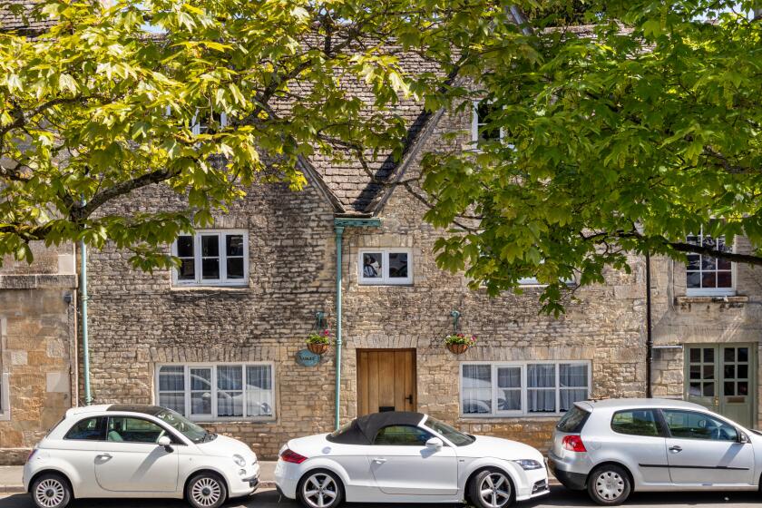Old stone houses and new cars in the Market Place in the ancient Cotswold town of Northleach, Gloucestershire UK