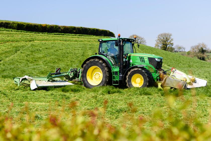 Farmer in a John Deere 6190 with front and rear disc grass cutters cuts the first crop of silage.