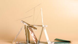 Crashed house of cards. Falling cards on beige background